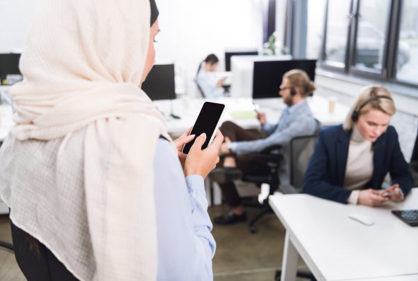 hijabi woman holding a smart phone in an office