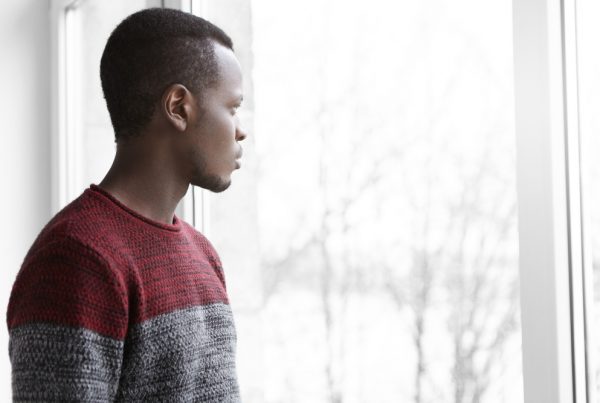 young black man looking out a window