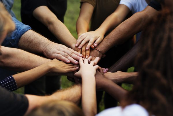 group of people with hands together in the center of a circle