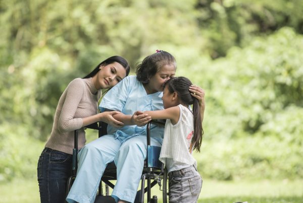 elder wheelchair user huggingyounger woman and child