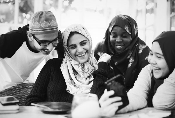 black and white image of four people, some wering head scarves, smiling