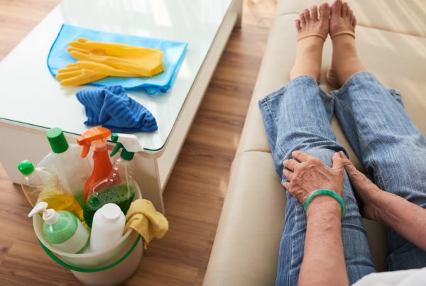 person holding injured knee with cleaning supplies nearby