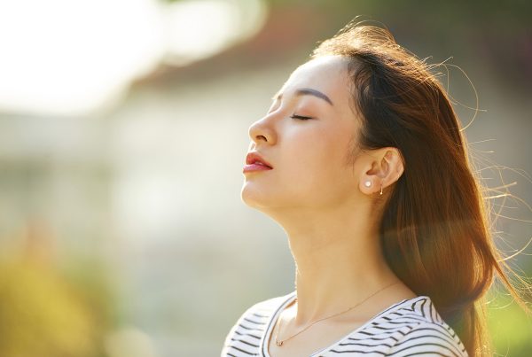 woman with eyes closed facing up towards the sun