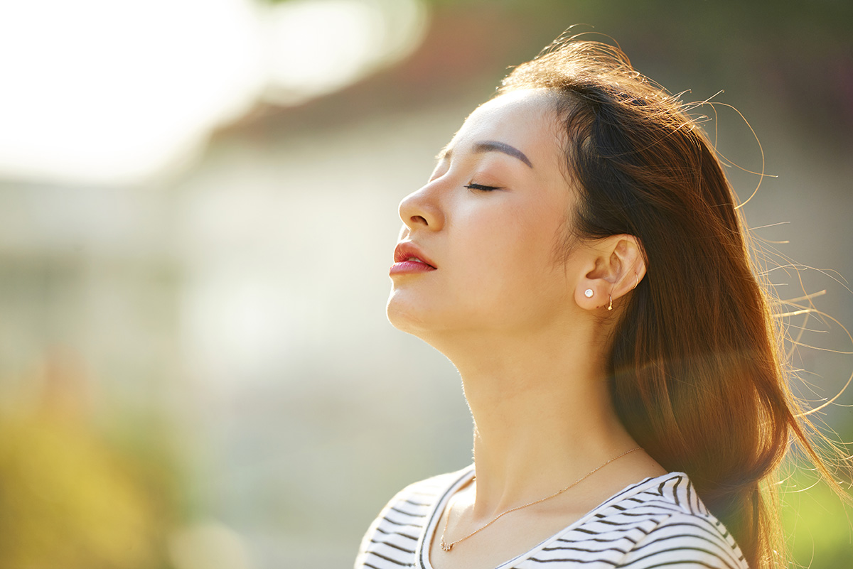 woman with eyes closed facing up towards the sun