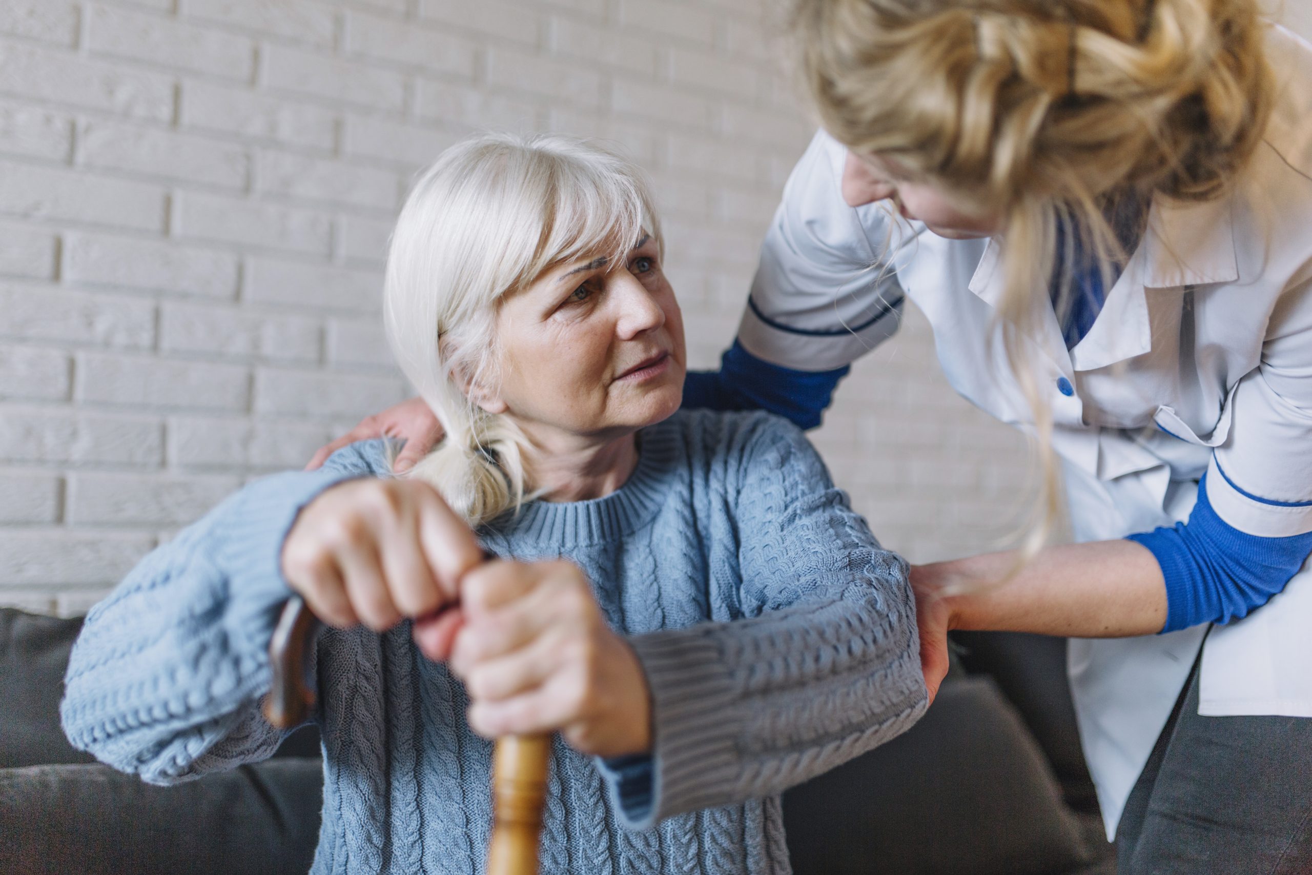 caregiver assisting a senior woman with a cane