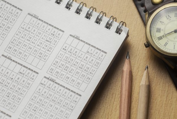 close up of calendar, clock, and pencils