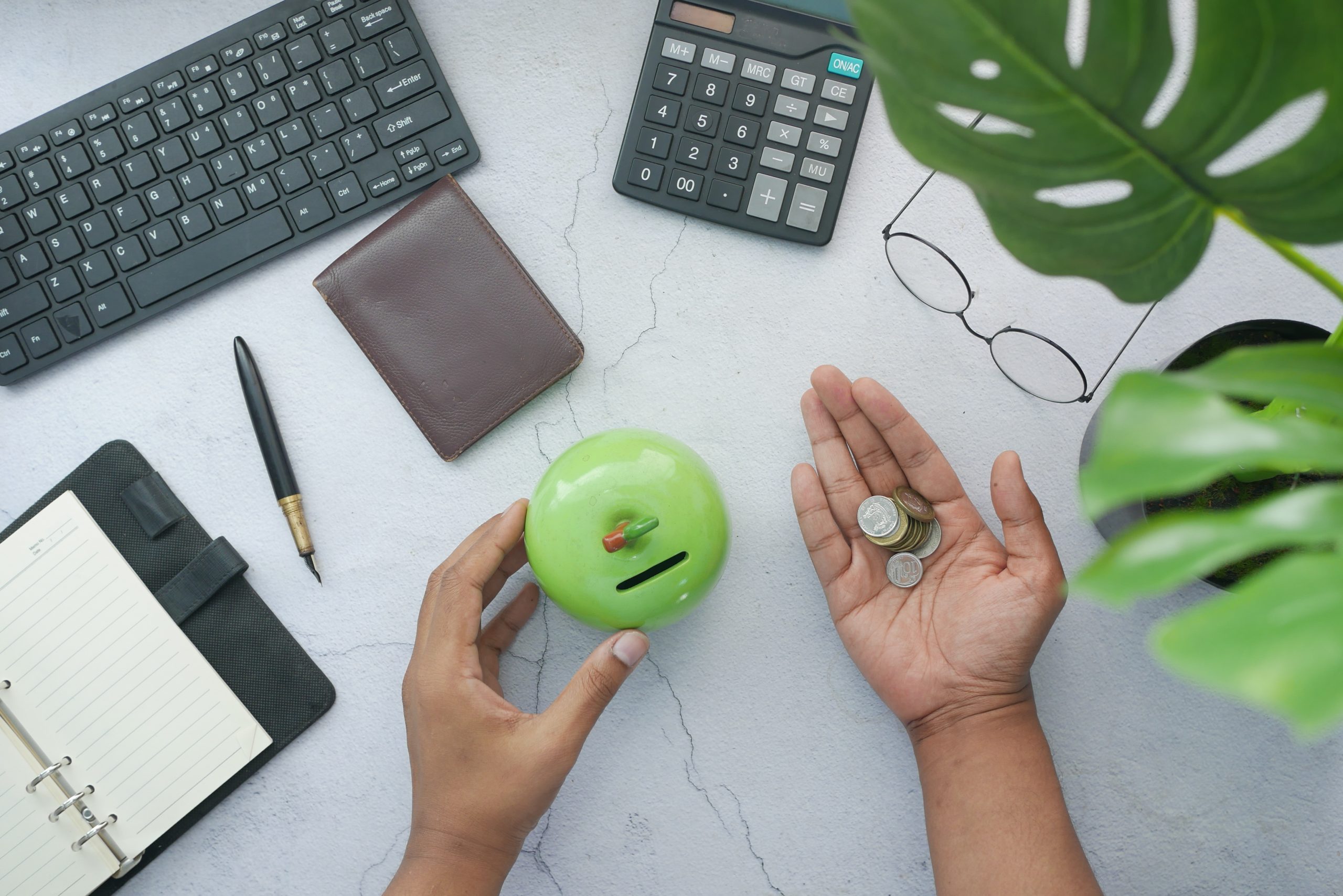 top view of desk with man holding coins and jar