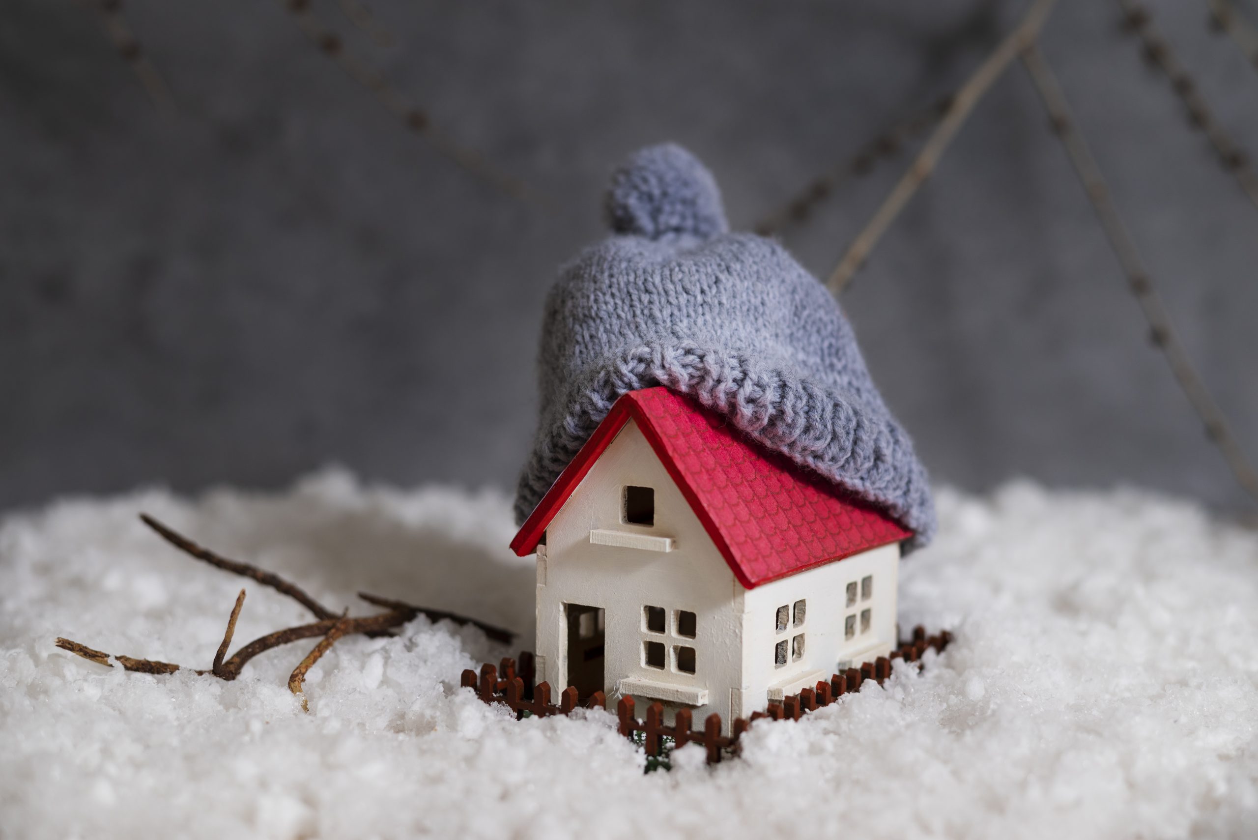 "Small model home in snow with a hat on the roof"